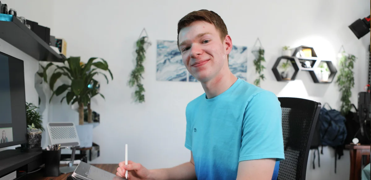 High school student wearing a light blue shirt taking notes at home