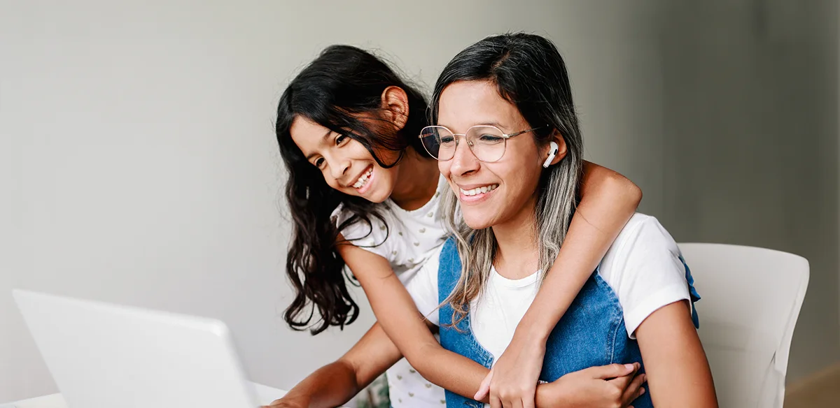 Mother and daughter smiling using their computer